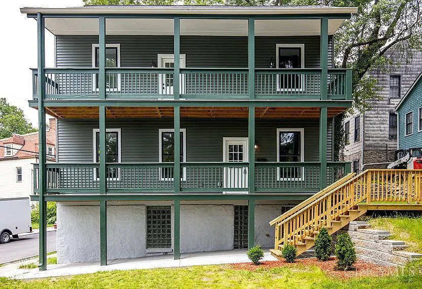 Dark green house with porches on two levels and a basement.