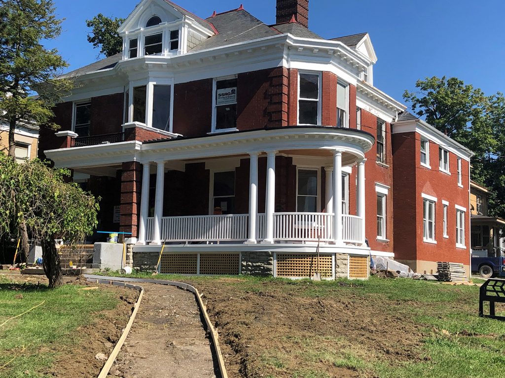 Image of large, historic single-family home structure on a corner lot featuring large, wraparound porch, multiple fireplaces, and historic exterior details.