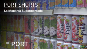 Image of brightly colored cans of juice lined up neatly on a shelf overlaid with the text "Port Shorts: La Monarca Supermercado"