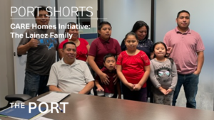 Image of a family standing behind a table with paperwork holding up a set of keys for their new home.