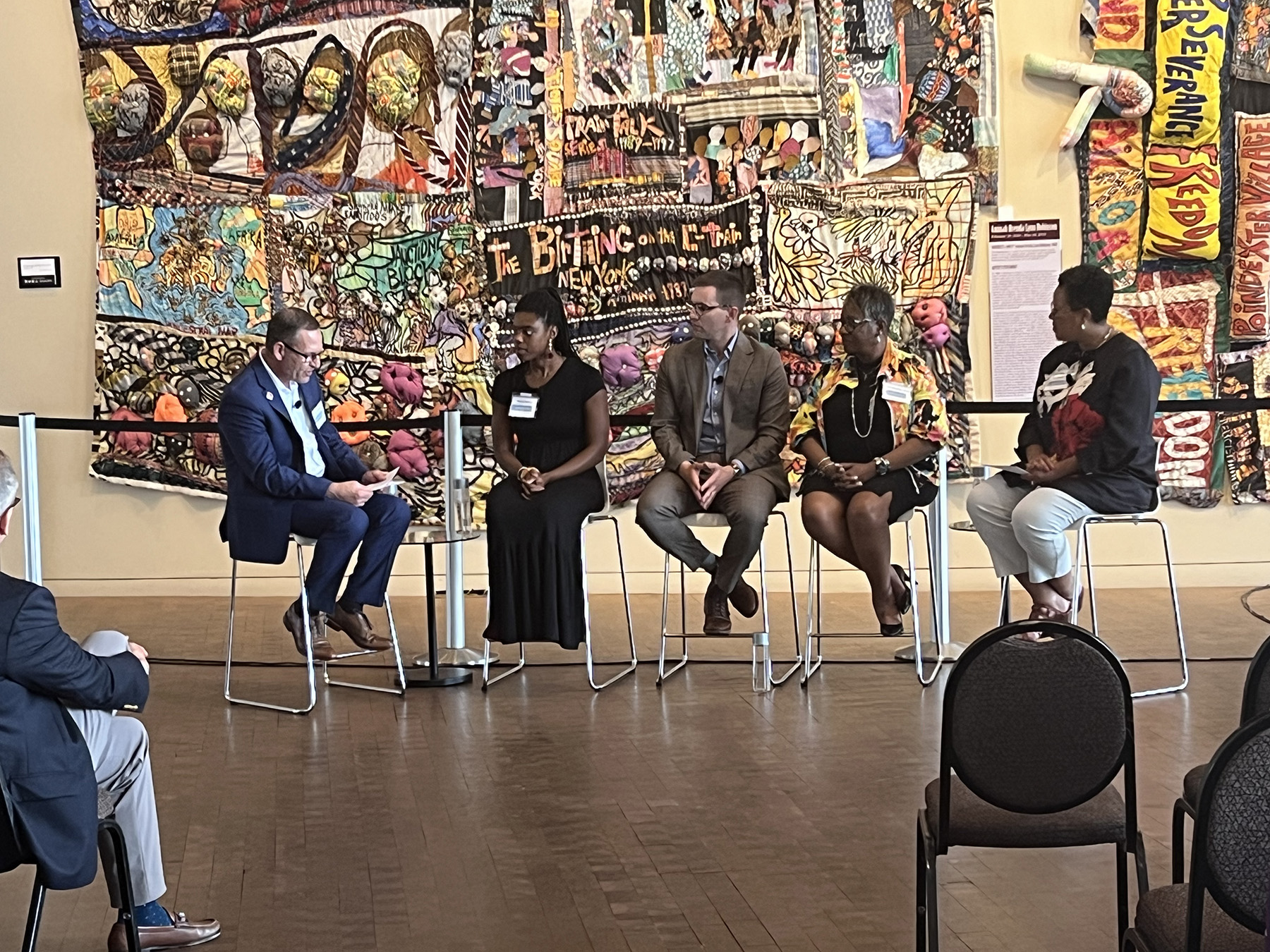 Red Cross Panel - May 2023 View of four panelists facing a moderator. In the backdrop is a quilt at the Freedom Center Museum.